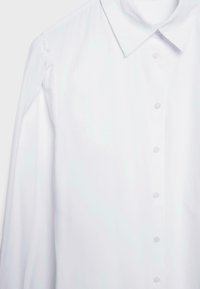 Chemise blanche à manches longues avec un col, fermeture à boutons sur le devant et détails froncés aux épaules, fabriquée en tissu lisse.