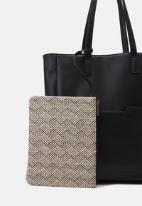 Czarna skórzana torba typu tote z dwoma uchwytami, w zestawie z zamykanym na zamek, teksturowanym etui w beżowo-czarny wzór.