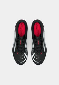 Μαύρα αθλητικά παπούτσια με υφή στο σιλουέτα, διακοσμημένα με λευκές λεπτομέρειες, κόκκινο πάτο και μαύρο σύστημα κορδονιών. Διακριτό μοτίβο στα πλευρά.