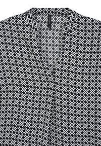 Blusa a fantasia geometrica in bianco e nero con colletto a V e etichetta del marchio visibile all'interno del colletto.