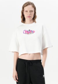 Tricou alb scurt, cu mâneci scurte, având text grafic colorat „Alethea Studio Edition” și accente negre pe un fundal simplu.