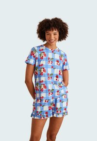 Blauwe en witte geruite pyjama set met kersen- en aardbei-patronen. T-shirt met korte mouwen en shorts met een gerimpelde zoom. Katoenen stof.