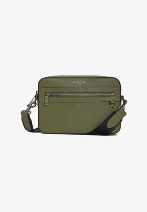 Bolso bandolera texturizado en verde oliva con un cierre superior y un bolsillo frontal. Presenta una correa negra y herrajes plateados. Diseño compacto y rectangular.