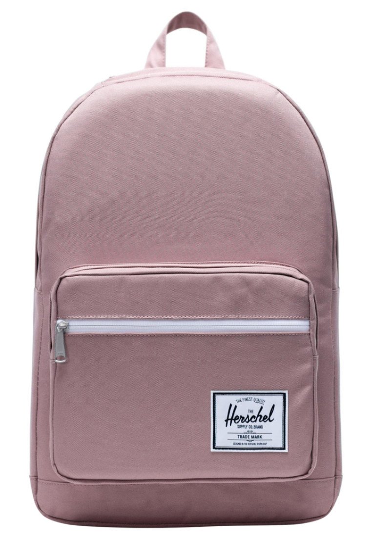 Zaino in tessuto rosa con forma arrotondata, tasca frontale con zip, dettagli bianchi e un'etichetta del marchio. Dotato di manico superiore e spallacci regolabili.