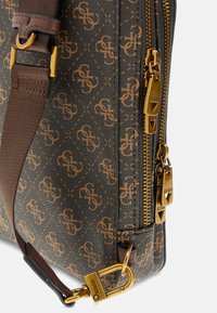 Borsa in pelle marrone con accessori dorati, caratterizzata da un motivo monogram. Include zip e una tracolla regolabile marrone per maggiore versatilità.