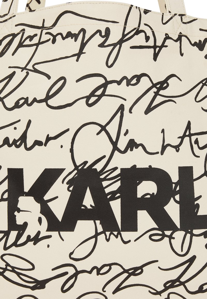 Canvas-Einkaufstasche in Creme mit schwarzem Kritzeltext und einem auffälligen "KARL"-Logo. Strukturiert mit einem vielfältigen Muster aus Unterschriften.