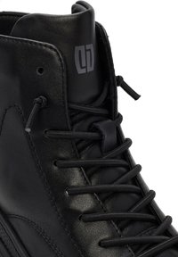 Sneaker high-top in pelle nera, con colletto imbottito, lacci neri e logo grigio sul lato. Texture liscia con punta arrotondata.