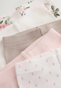 Cztery pary prążkowanych legginsów w kolorach: kremowo-białym, jednolitym białym, beżowym oraz jasnoróżowym z drobnymi wzorami kwiatowymi. Widoczny jest detal w postaci fakturowanego materiału.