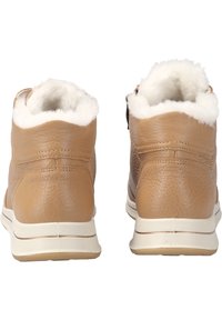 Stivaletti in pelle marrone con fodera in pelliccia bianca, suola piatta in gomma beige e dettagli di cucitura discreti sul tallone e sulle sezioni superiori.