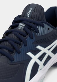 Zapatilla deportiva en navy con upper de malla, logo blanco en contraste, detalles texturizados y cordones redondos. La suela tiene un acento blanco.