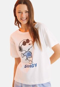 Maglietta bianca in cotone con un cartone di Snoopy che indossa occhiali da sole, con "JOE COOL" stampato sulla maglietta e "snoopy" in testo blu qui sotto.
