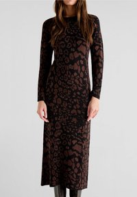 Langärmliges, figurbetontes Kleid aus schwarzem Stoff mit einem braunen Leopardenmuster. Knielang mit glatter Textur.