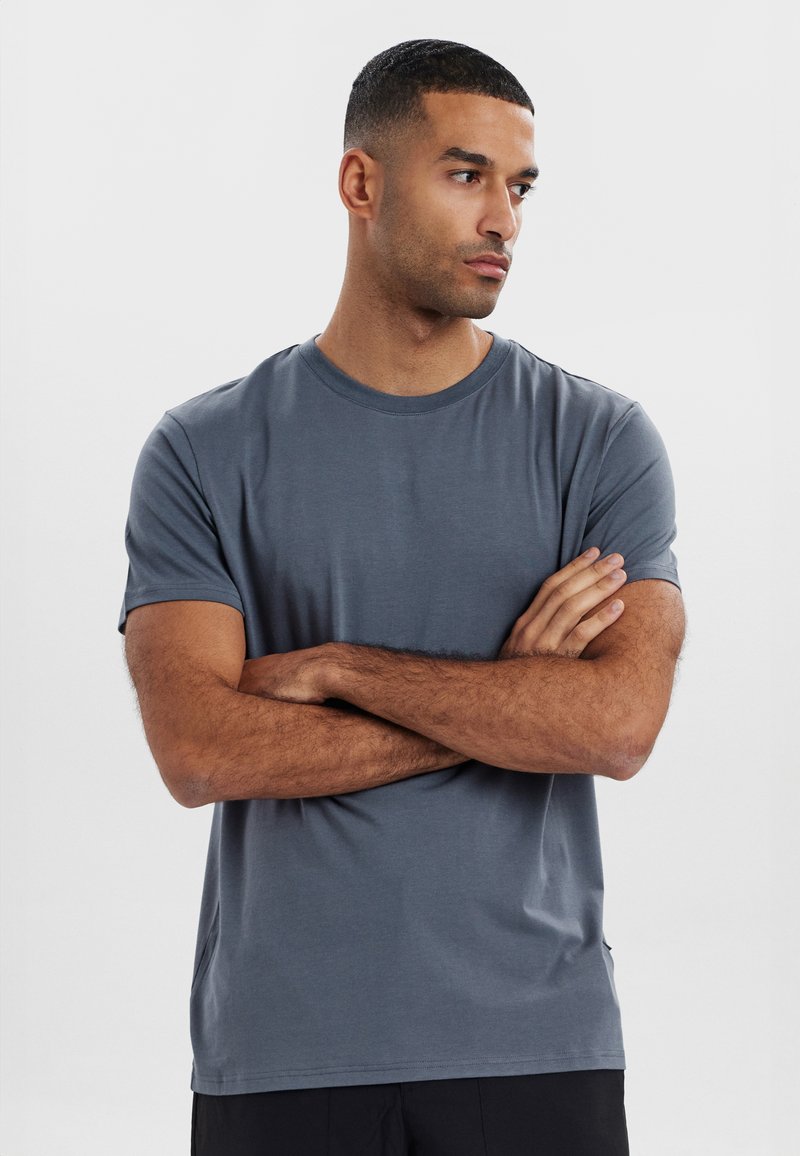 Grå t-shirt med korte ærmer i et blødt, glat stof med rund halsudskæring og detalje i siden. Pasformen er almindelig og komfortabel.