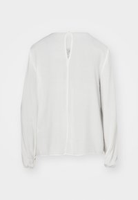Camicetta bianca a maniche lunghe realizzata in tessuto leggero, con apertura a chiave sul retro e polsini arricciati. Texture liscia con design minimal.
