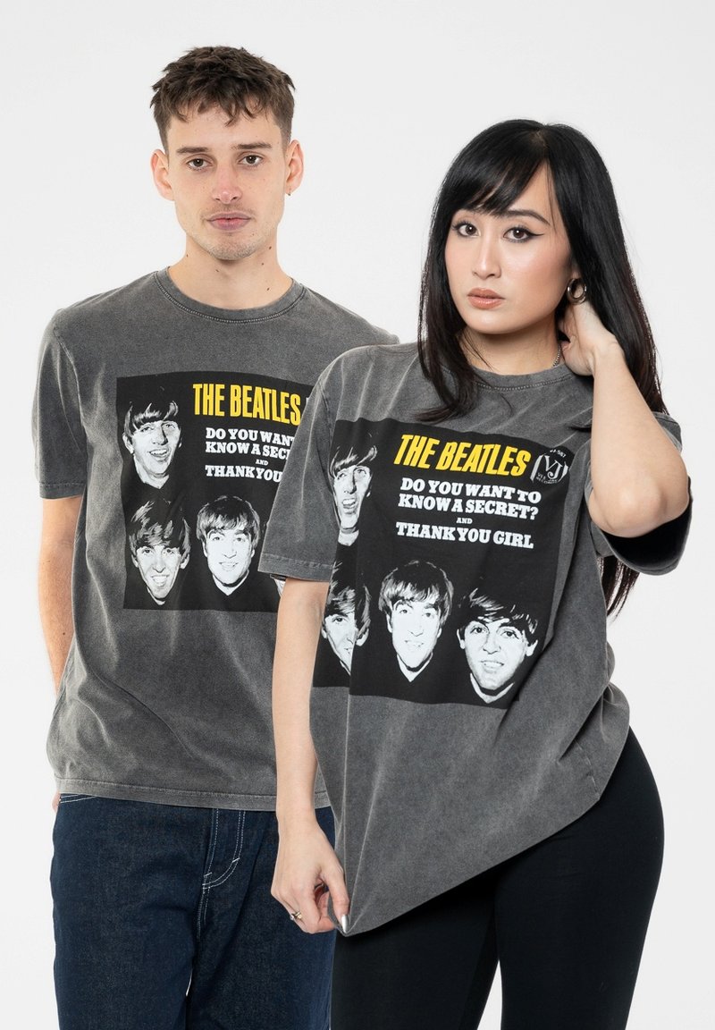 Gray cotton t-shirts featuring The Beatles graphic print, square design with black and white faces, yellow text, and relaxed fit on model.
