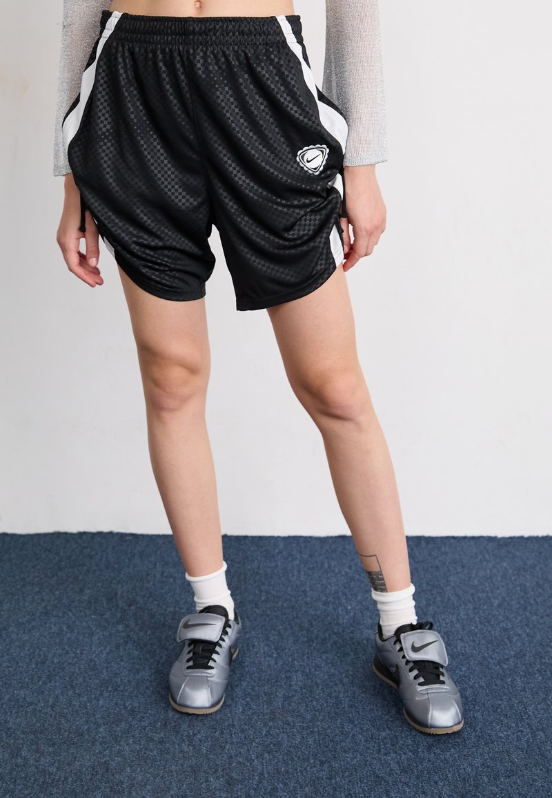 Black athletic shorts made of mesh fabric, featuring a checkered pattern, white side stripes, and a logo on the front.