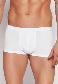Białe bawełniane bokserki o dopasowanym kroju, z markowym elastycznym paskiem w białym i czerwonym kolorze. Gładka tekstura, bez widocznych wzorów.