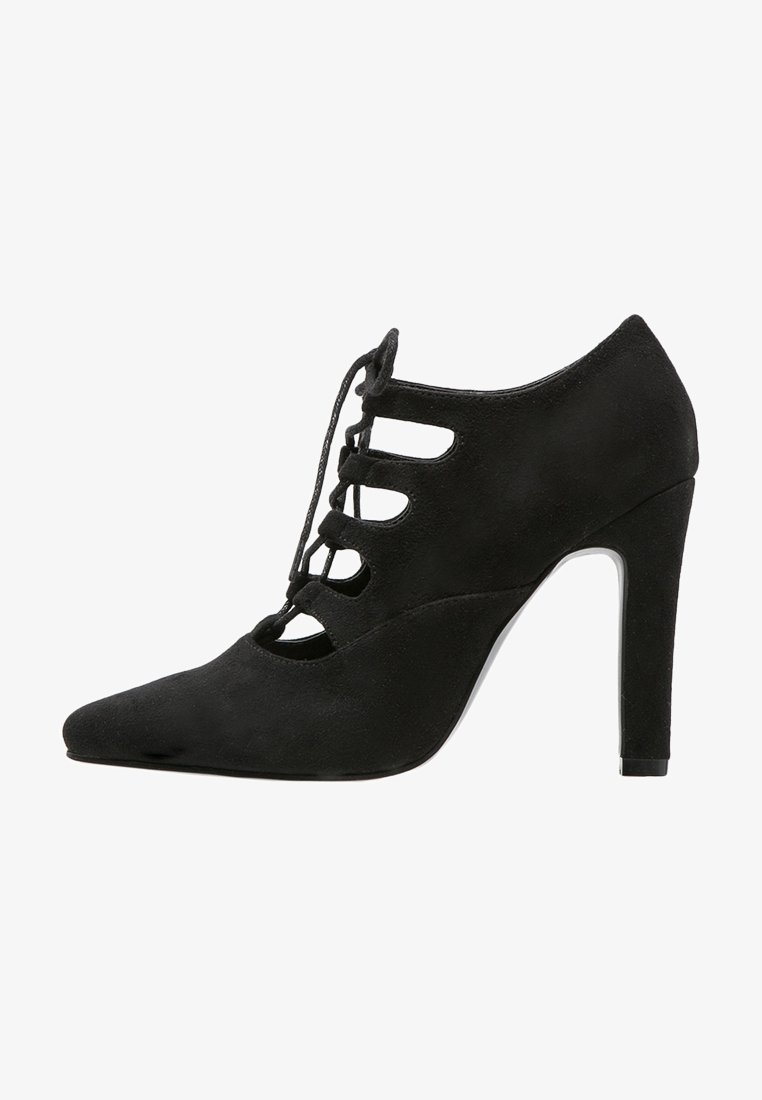 Chaussure à talon haut en daim noir avec bout pointu et design ajouré à lacets sur le devant et le côté.