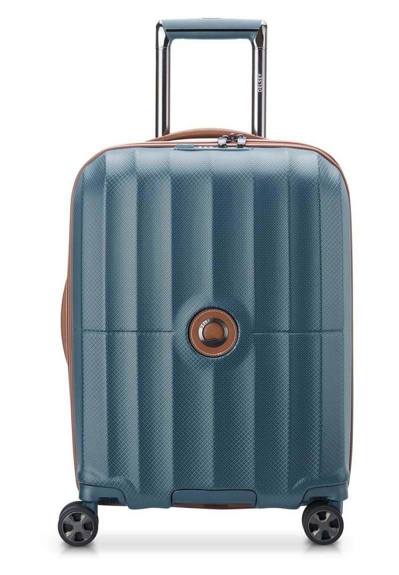 Valigia rigida blu con scanalature diagonali testurizzate, dettagli marroni, maniglia telescopica e quattro ruote nere per la mobilità.