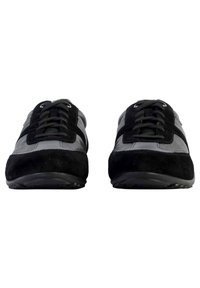 Baskets noires et grises en cuir et daim, avec un design à lacets, des semelles plates et des bandes décoratives sur le dessus.