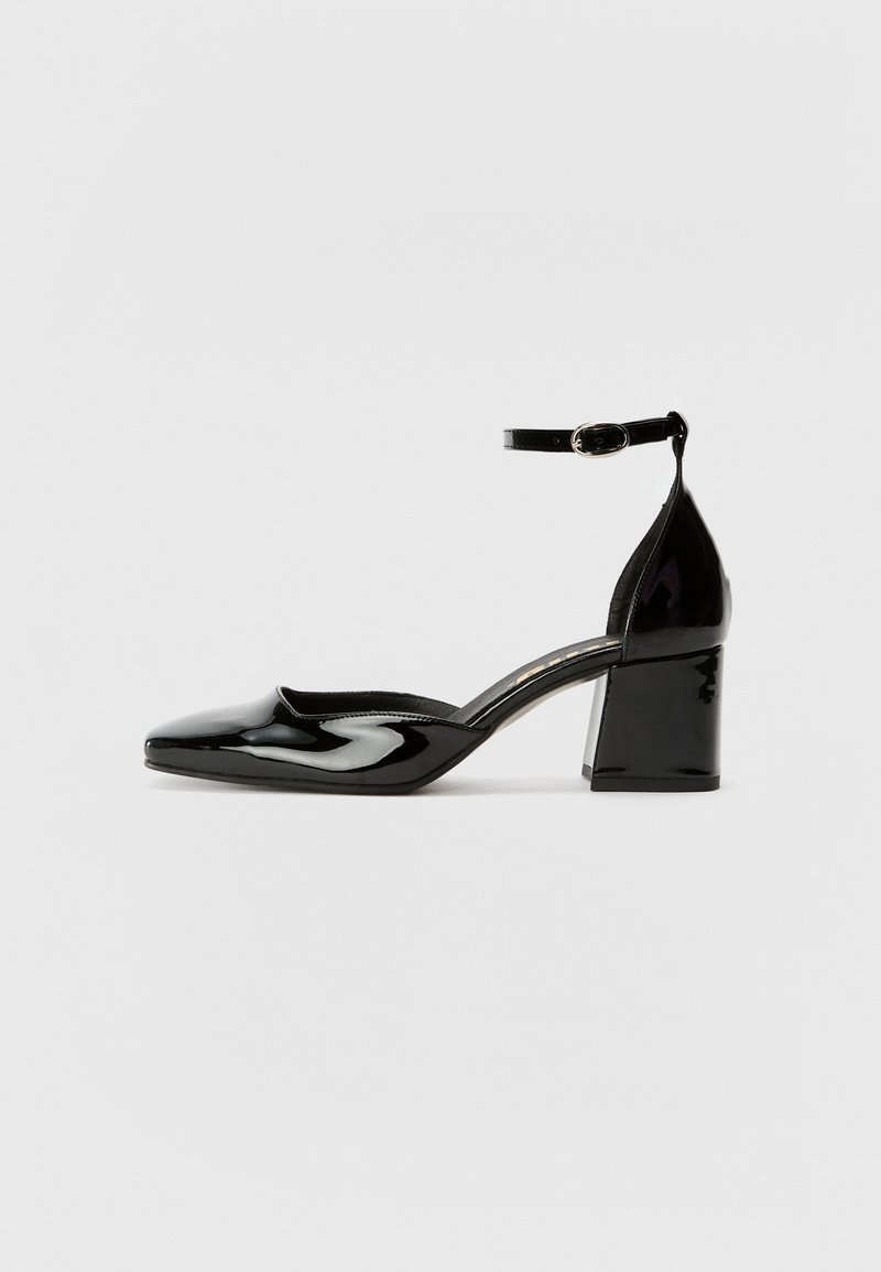 Shoe de salto alto em couro liso preto com bico fino, faixa no tornozelo e salto robusto, apresentando uma superfície suave e brilhante.