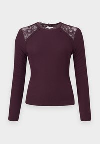 Langsleeve, ribbeltop in diep bordeaux met kantaccenten op de schouders en een ronde halslijn, voorzien van een knoopsluiting aan de achterkant.