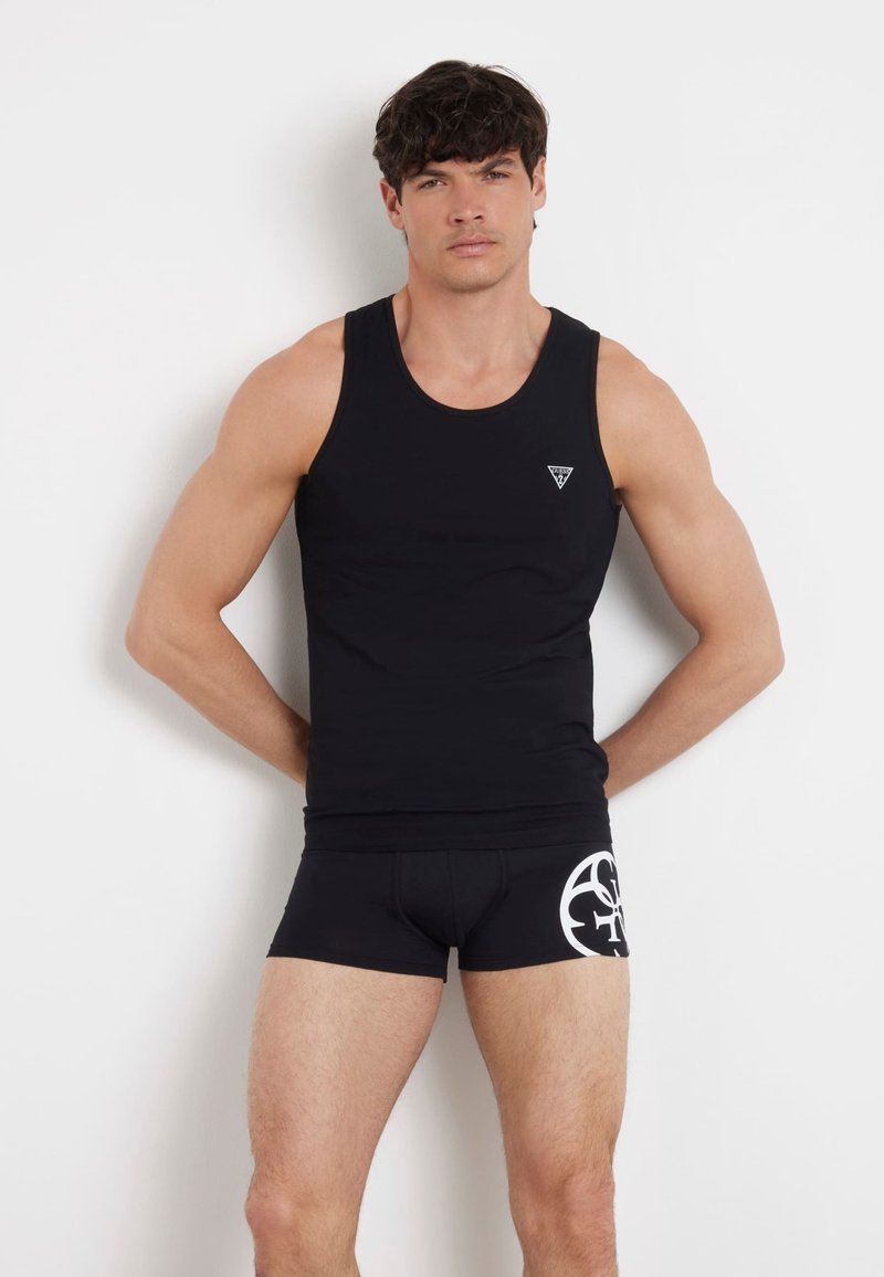 Schwarzes Tanktop mit kleinem Logo auf der Brust, kombiniert mit schwarzen Boxershorts mit einem weißen grafischen Design. Glatte Textur, figurbetontes Design.