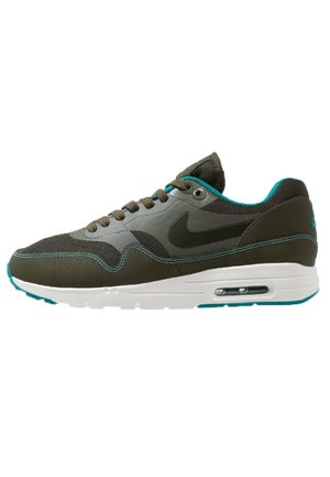 Mørkegrøn og grå Nike sneaker med turkis accenter, hvid sål med synlig luftpude og snørelukning foran vist fra siden.