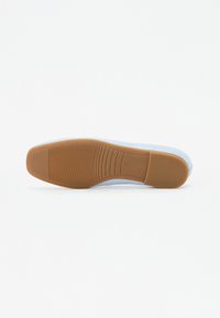 Semelle de chaussure bleu clair en matériau caoutchouteux, avec une surface texturée et des stries horizontales pour une meilleure traction. Bords lisses et design simple.