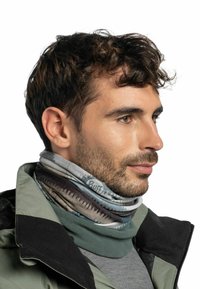 Cuello multicolor que presenta capas de tela con un patrón de zigzag, en tonos de gris, azul y verde, que se lleva con una chaqueta.