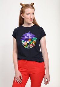 Granatowy t-shirt z kolorowym nadrukiem "Czas na herbatę", przedstawiającym postacie, kwiaty i grzyby; stylizowany z czerwonymi spodniami.