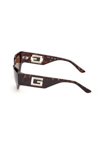Lunettes de soleil écaille avec des branches épaisses ornées de grands logos rectangulaires argentés de chaque côté.