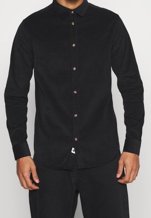 Camicia nera con bottoni neri realizzata in cotone testurizzato, con colletto aperto, maniche lunghe e bottoni marroni sul davanti, modellata per una vestibilità comoda.
