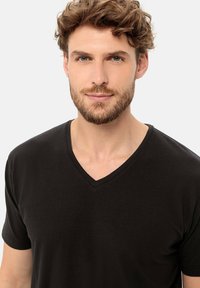 Zwarte v-hals t-shirt van zacht katoen. Korte mouwen, een gladde textuur en een casual pasvorm. Eenvoudig ontwerp zonder patronen of logo's.