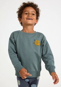 Sweatshirt verde com personagem de desenho animado amarelo texturizado no peito, gola redonda, punhos e barra canelados; tecido macio.