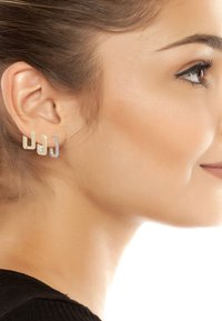 Boucles d'oreilles en or et argent présentant des formes géométriques, dont une pièce intègre une perle et l'autre est ornée de petites pierres claires.