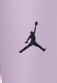 Silhouette nera di una figura che salta su un tessuto viola chiaro. Il design presenta una pallacanestro nella mano alzata della figura.