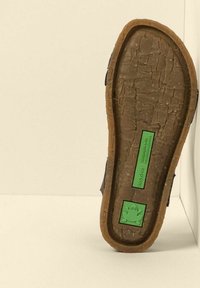 Podešev boty vyrobená z texturované hnědé gumy s zelenou etiketou s nápisem "Recyclus" a logem žáby, ukazující robustní, opotřebovaný design.