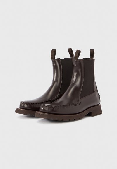 Stivaletti alla caviglia in pelle marrone con pannelli laterali elasticizzati, dettagli di cuciture testurizzate e suola in gomma spessa. Linguette per facilitare la calzata.