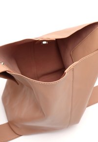 Borsa a secchiello in morbida pelle rosa con un design senza cuciture, apertura superiore e texture liscia. L'interno presenta un unico compartimento senza tasche aggiuntive.