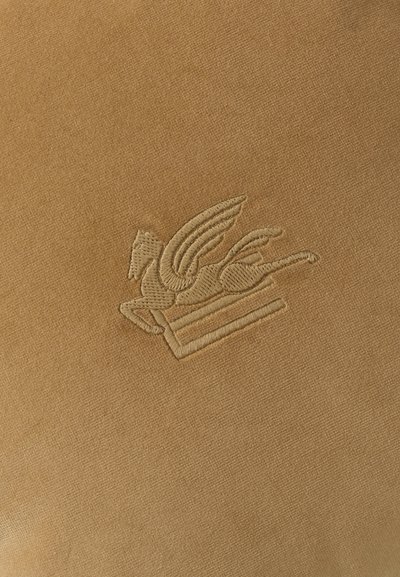 Tissu beige avec un cheval ailé brodé (Pégase) au-dessus de deux lignes horizontales en fil beige assorti.