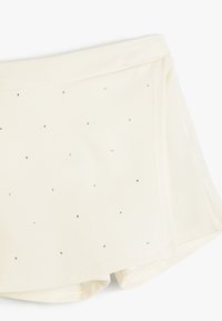 Shorts cremosos hechos de una tela suave, con una textura lisa, adornados con pequeños strass plateados distribuidos uniformemente por la superficie.