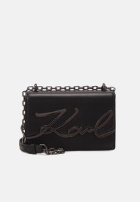 Borsa a tracolla nera in pelle con logo "Karl" lucido, tracolla a catena e forma rettangolare; texture liscia con dettagli di design minimalisti.