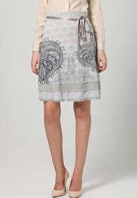 Falda de patrón gris y blanco con diseño de paisley, borde de encaje y lazo de satén en la cintura. Confeccionada con una tela ligera.