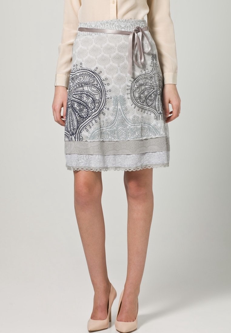 Falda de patrón gris y blanco con diseño de paisley, borde de encaje y lazo de satén en la cintura. Confeccionada con una tela ligera.