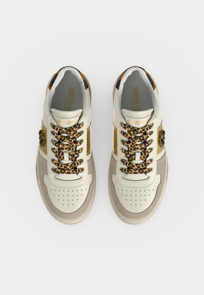 Paire de baskets blanches et beiges avec des lacets à imprimé léopard et des accents dorés, vues de dessus sur un fond uni.