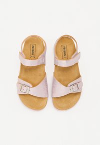 Ljust rosa sandaler med en texturerad yta, med två justerbara remmar och en silverfärgad spänne, på en naturligt tan fotbädd.