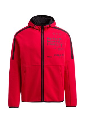Veste à capuche zippée rouge avec un intérieur noir, présentant du texte imprimé et des accents. Deux poches latérales zippées avec des garnitures noires le long des manches.