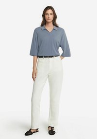 Ljusblå kortärmad polo med v-ringning, kombinerad med högmidjade vita jeans och svarta vävda sandaler, med en smal passform och minimalistisk design.