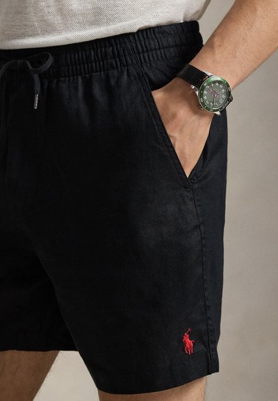 Μαύρο λινό σορτς με ελαστική μέση και κορδόνι, με μικρό κόκκινο κεντημένο λογότυπο στο τελείωμα. Μινιμαλιστικός σχεδιασμός, ομαλή υφή.